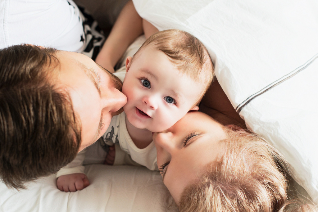 Familia sonriente besando a su bebé