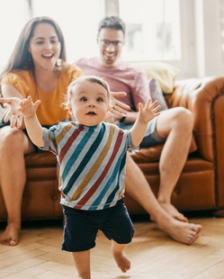 bebe caminando descalzo por su casa y padres felices